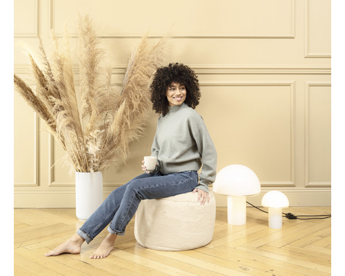 Femme assise sur un pouf dans un salon avec décoration et lampes champignons