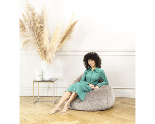 Frau sitzt auf einem grauen Sitzsack in einem Wohnzimmer