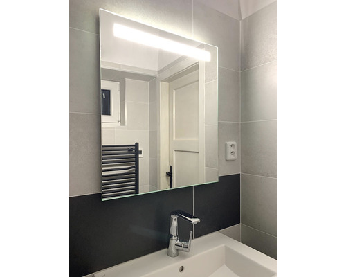 Salle de bains avec miroir et éclairage au-dessus d''un lavabo avec robinet