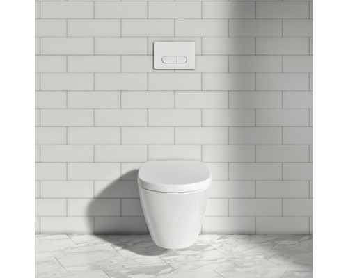 Wandhängendes WC mit Betätigungsplatte vor einer gefliesten Wand