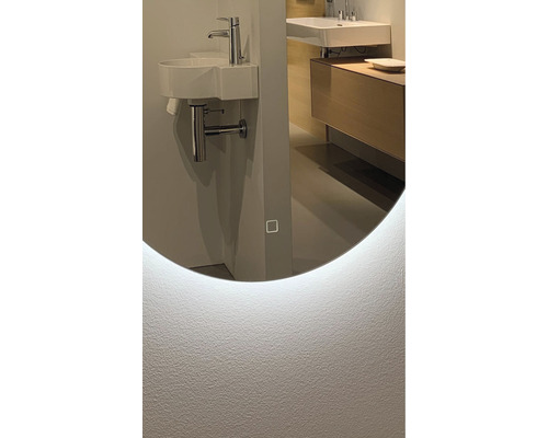 Detailansicht eines Badezimmers mit einem runden Spiegel mit LED-Beleuchtung, Waschbecken und Armatur