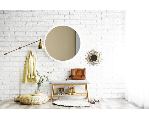 Espace d''entrée avec miroir, banc, lampadaire et décorations devant un mur de briques blanches