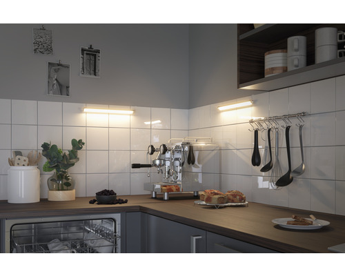 Scène de cuisine avec évier, vaisselle, ustensiles de cuisine et luminaires sous meuble haut