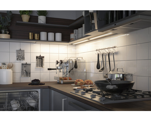 Scène de cuisine avec des étagères, des éclairages sous armoires, des ustensiles de cuisine et des appareils sur le plan de travail.