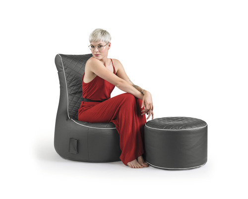 Une femme est assise dans un fauteuil avec un tabouret