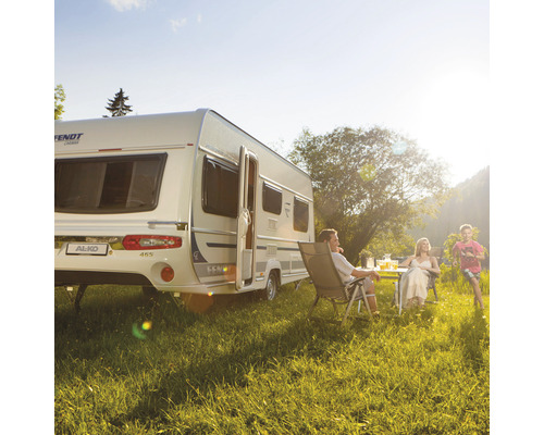 Famille se détend devant une caravane sur une prairie