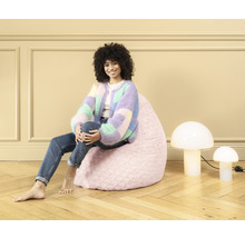 Femme assise sur un pouf rose, à côté de deux lampes champignons