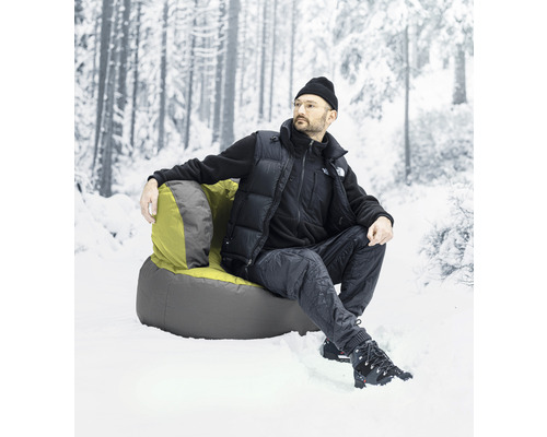 Un homme est assis dans un fauteuil dans la neige devant une forêt floue