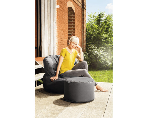 Femme assise dans un pouf gris avec repose-pieds à l''extérieur