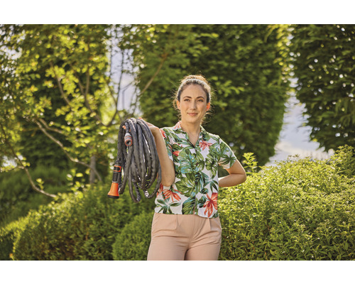 Femme tenant un tuyau d''arrosage dans le jardin.