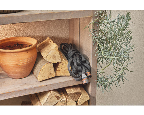 Étagère en bois avec pot de fleurs, bois de chauffage, tuyau d''arrosage et plante verte