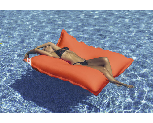 Frau entspannt auf einer orangefarbenen Poolinsel im Wasser.