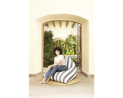 Femme assise sur un pouf rayé à l''extérieur.