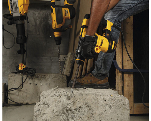 Un artisan utilise un marteau-piqueur DeWalt pour travailler le béton. D'autres marteaux perforateurs sont prêts en arrière-plan.