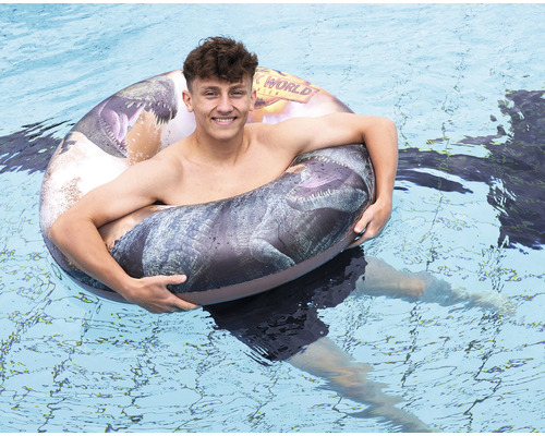 Une personne nage avec une bouée Jurassic World dans la piscine.