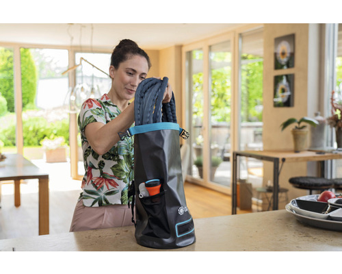 Femme range un tuyau d''arrosage dans un sac de rangement à l''intérieur