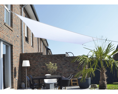 Terrasse avec voile d''ombrage, table et chaises devant un mur en briques
