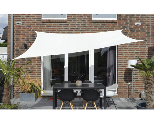 Terrasse mit Sonnensegel, Tisch und Stühlen vor einer Hauswand