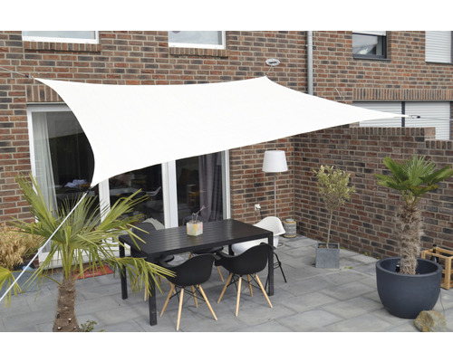 Terrasse mit Sonnensegel, Tisch und Stühlen vor einem Backsteingebäude