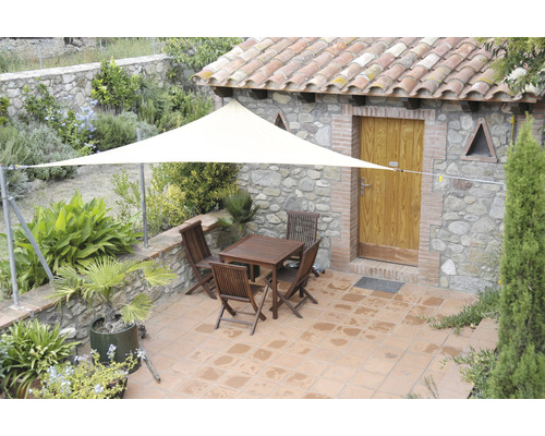 Extérieur avec voile d''ombrage triangulaire, table et chaises sur une terrasse.