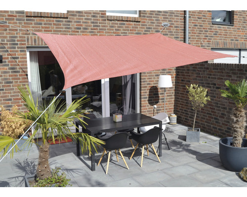 Terrasse avec voile d''ombrage, table et chaises devant un bâtiment en briques