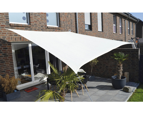 Terrasse avec voile d''ombrage triangulaire et mobilier de jardin devant une maison en briques