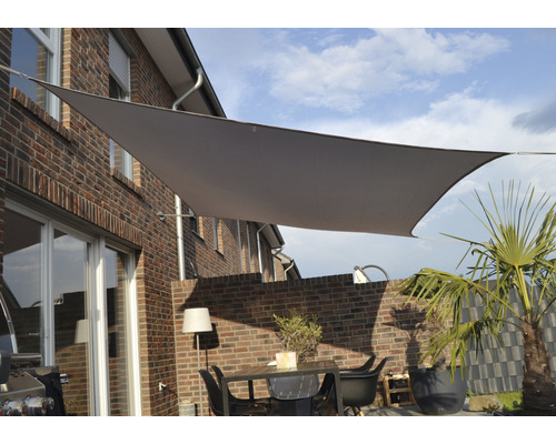 Terrasse avec voile d''ombrage, table et chaises devant une maison en briques