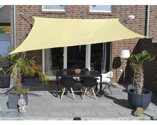 Terrasse mit Sonnensegel, Tisch und Stühlen vor einem Backsteingebäude