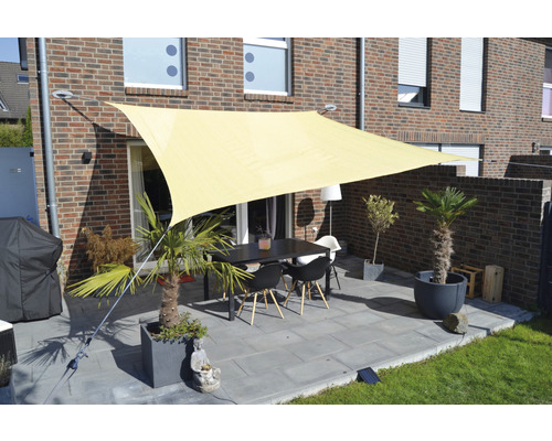 Terrasse mit Sonnensegel, Tisch und Stühlen vor einem Backsteinhaus