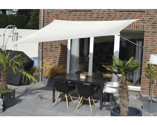 Terrasse mit Sonnensegel, Gartentisch und Stühlen vor einer Hauswand