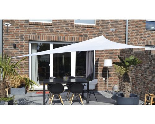 Terrasse avec voile d''ombrage, table et chaises devant une maison en briques