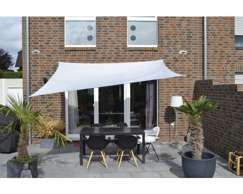Terrasse avec voile d''ombrage, table et chaises devant une maison