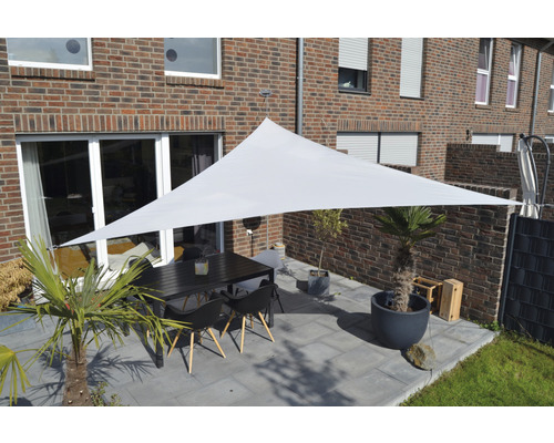 Terrasse avec voile d''ombrage triangulaire, table et chaises devant une maison en briques