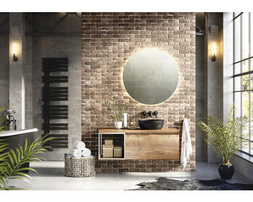 Salle de bains moderne avec lavabo, miroir, sèche-serviettes et baignoire devant un mur de briques