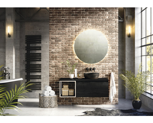 Salle de bains style loft avec lavabo, miroir, radiateur et baignoire devant un mur en briques