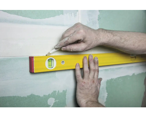 Eine Wasserwaage wird verwendet, um eine Linie an einer Wand zu markieren.