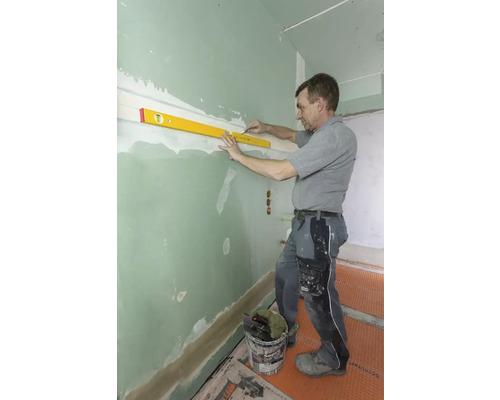 Handwerker richtet Wand mit Wasserwaage aus.