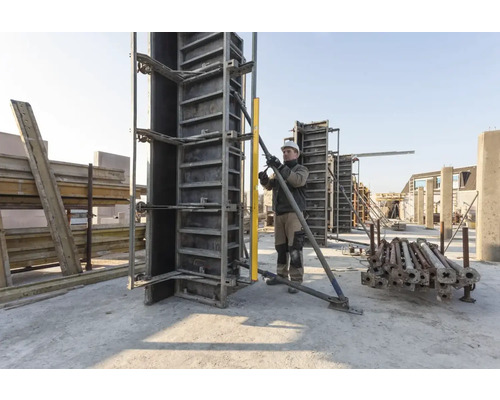 Bauarbeiter richtet Betonschalung mit Wasserwaage auf einer Baustelle aus.