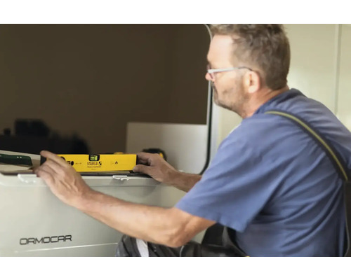 Handwerker benutzt eine Wasserwaage von Stabila auf einem Fahrzeug von Ormocar.