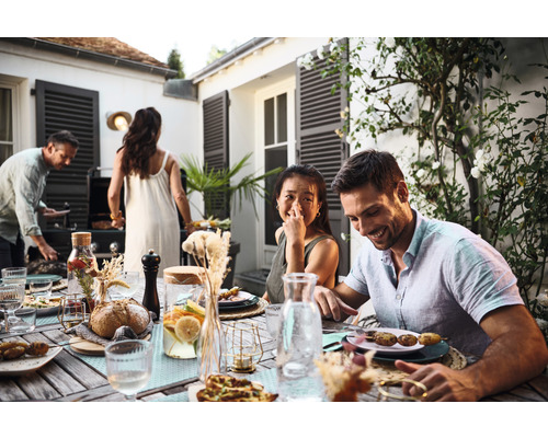 Szene mit einer Gruppe von Menschen, die im Freien an einem Tisch sitzen und grillen