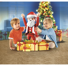 Deux enfants avec une figurine de Noël Playmobil et des cadeaux devant un sapin de Noël.