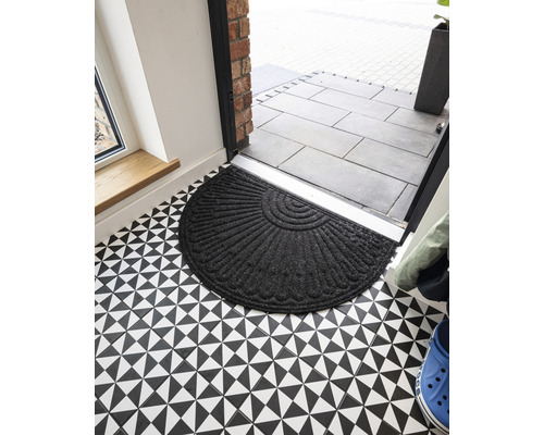 Paillasson demi-lune en textile devant une porte d''entrée sur un sol à motifs géométriques