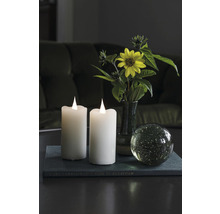 Scène décorative avec deux bougies électroniques, une fleur et une boule de verre