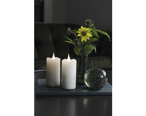 Scène décorative avec deux bougies électroniques, une fleur et une boule de verre