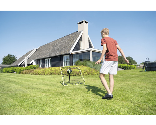 Junge spielt mit Fussballtor im Garten vor einem Wohnhaus