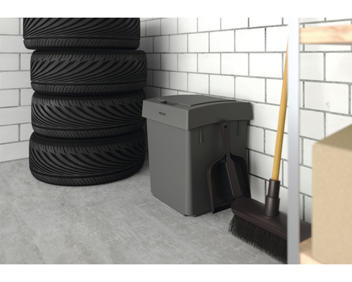 Scène d''un garage avec une pile de pneus, une poubelle grise avec couvercle, une pelle à poussière et un balai