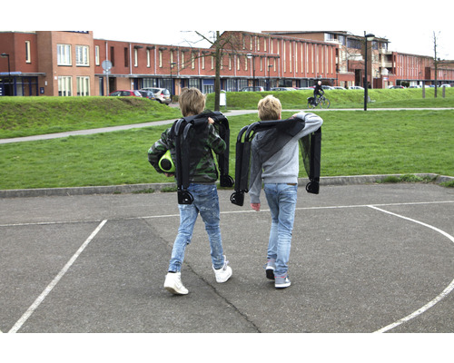 Deux enfants portent des chariots pliés dans une cour d''école.