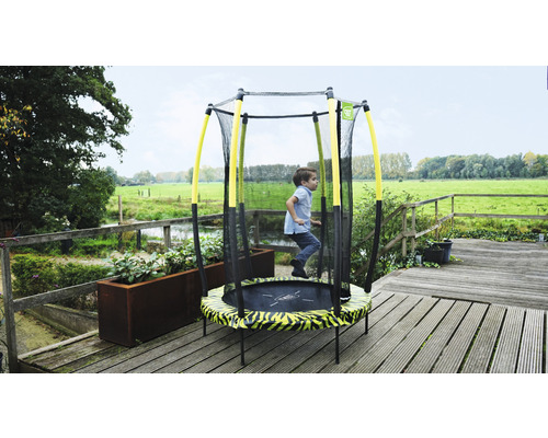 Enfant sautant sur un trampoline de jardin avec filet de sécurité.