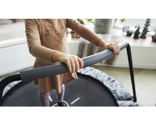 Un enfant s''accroche à un trampoline rond pour enfants, de coloris gris