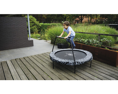 Garçon sautant sur un trampoline de jardin rond avec une poignée